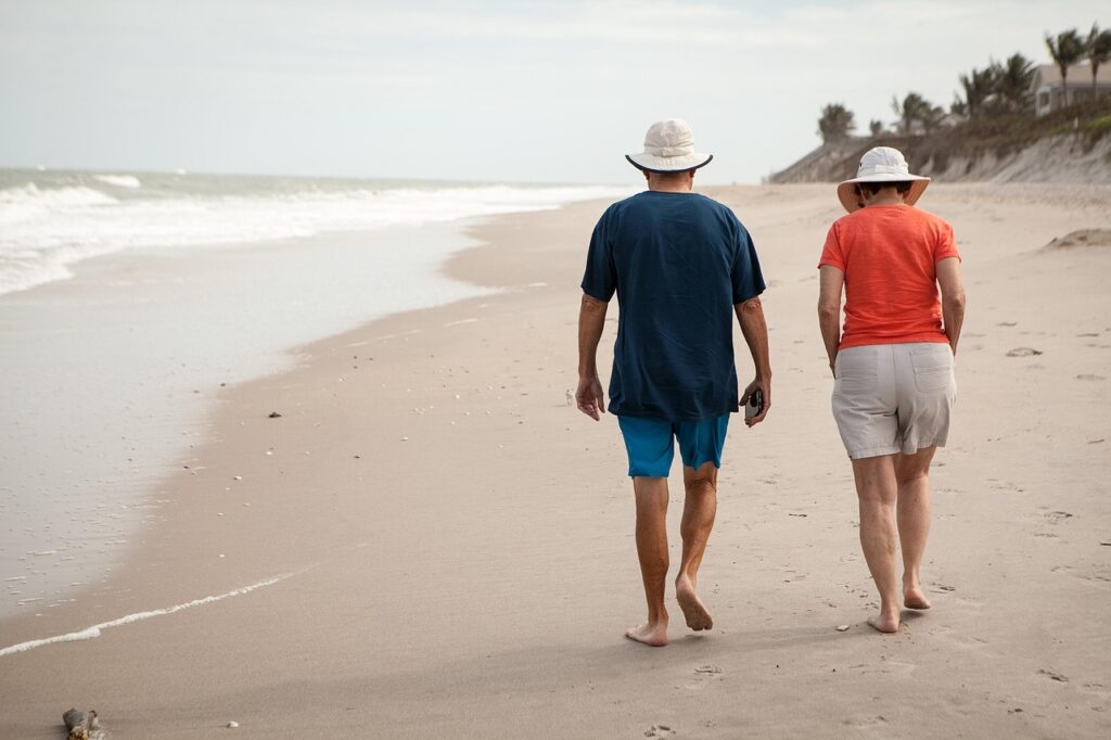 Two older persons walking along a beach